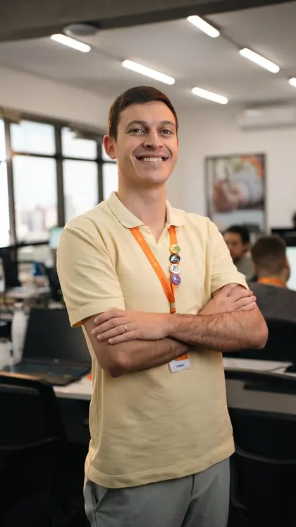 Trainee da Rottas de braços cruzados, sorrindo no escritório