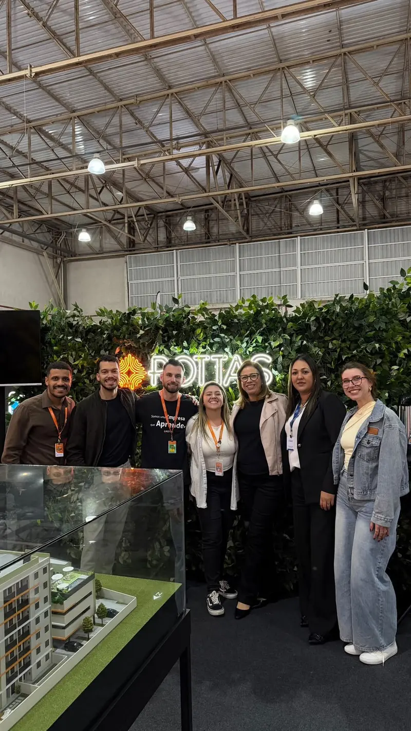 Time da Rottas em stand de vendas, diante da maquete de um empreendimento